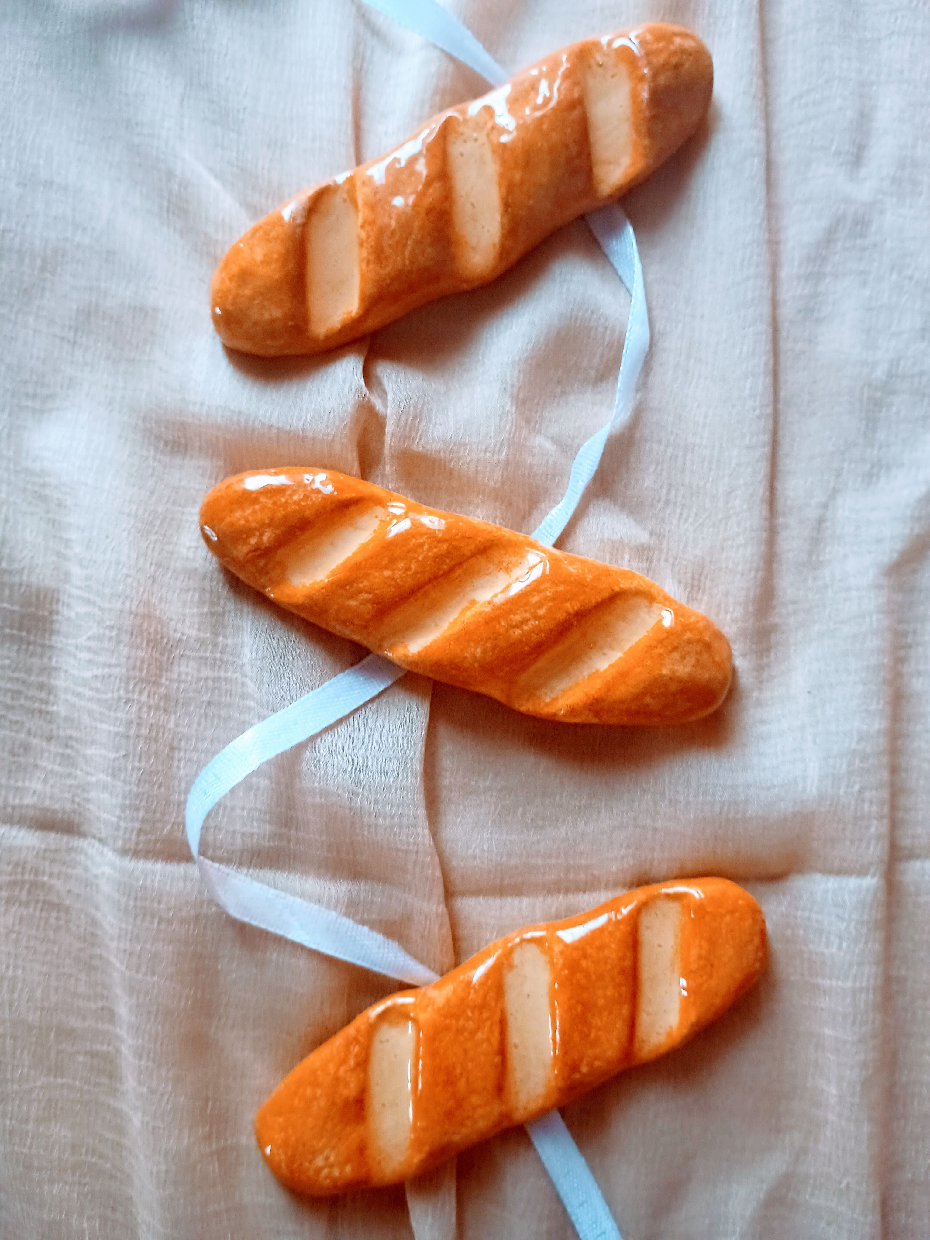 Three baguette-shaped clay pen rest  on a light fabric background