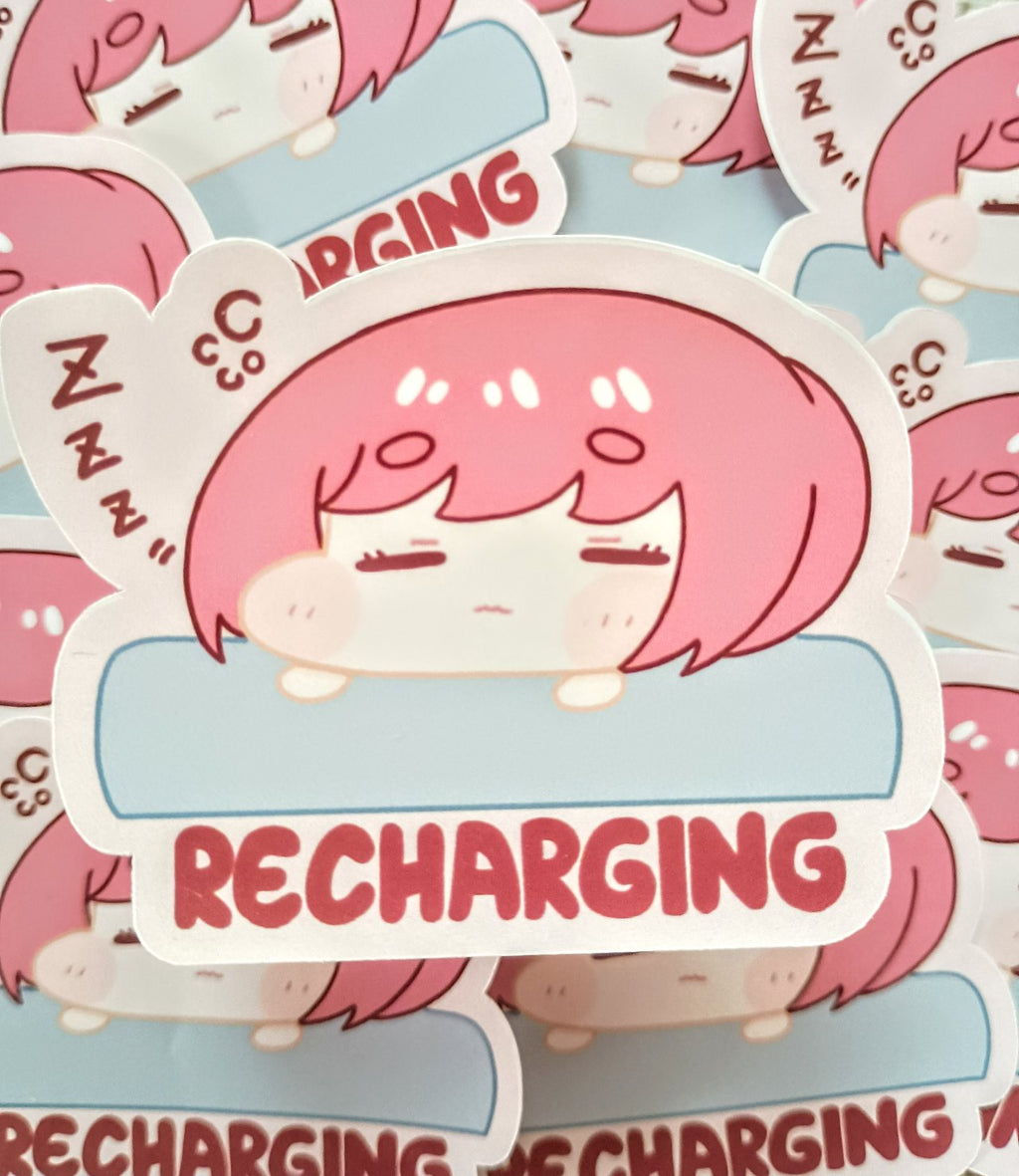 sticker with a pink haired girl resting on cushion to recharge her social battery with text below wriiten recharging.