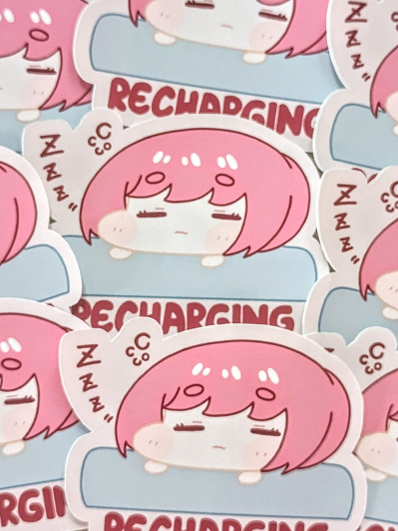 Sticker design with a character with pink hair girl and 'RECHARGING' text on a blue background