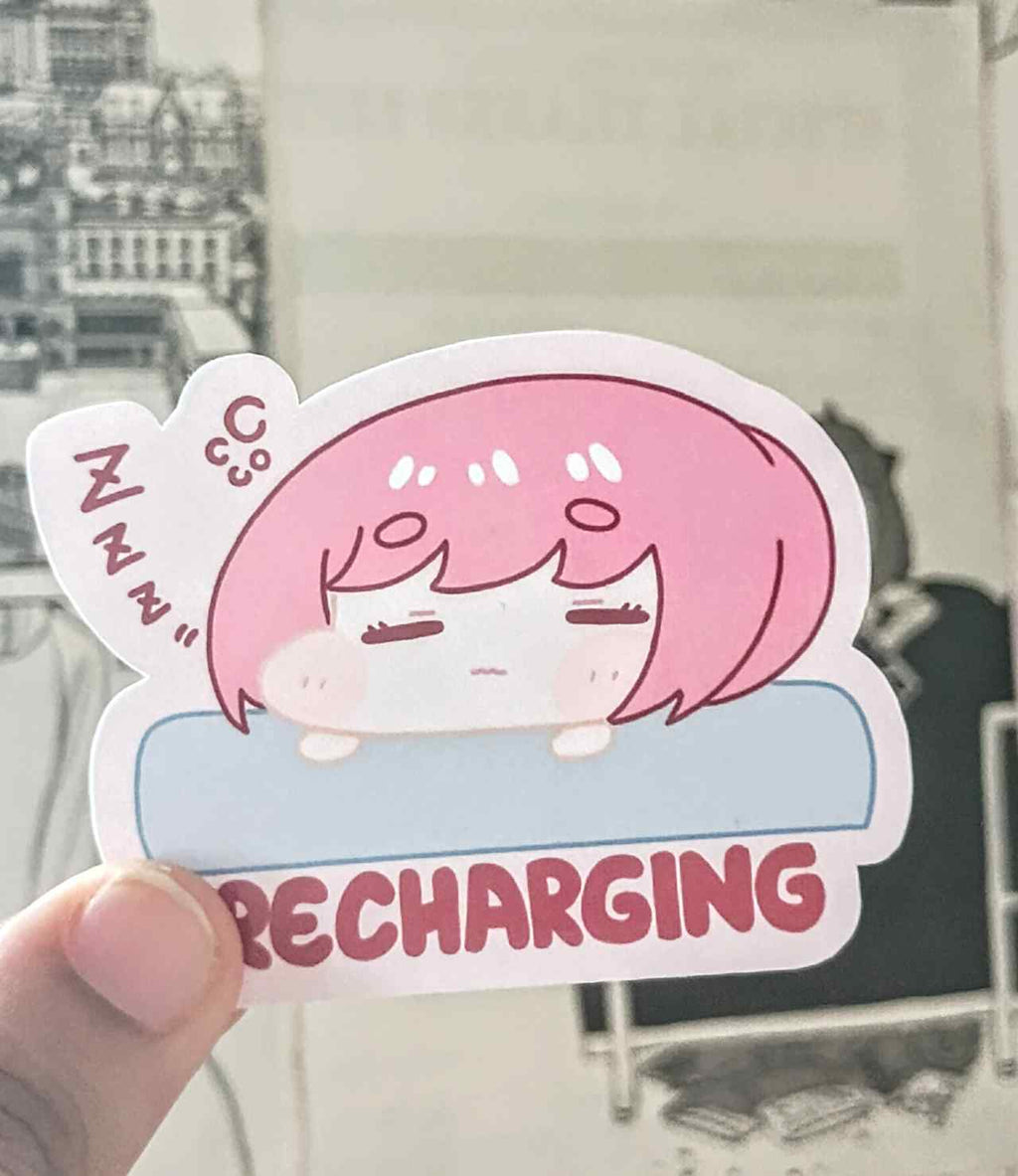 sticker with a pink haired girl resting on cushion to recharge her social battery with text below wriiten recharging.