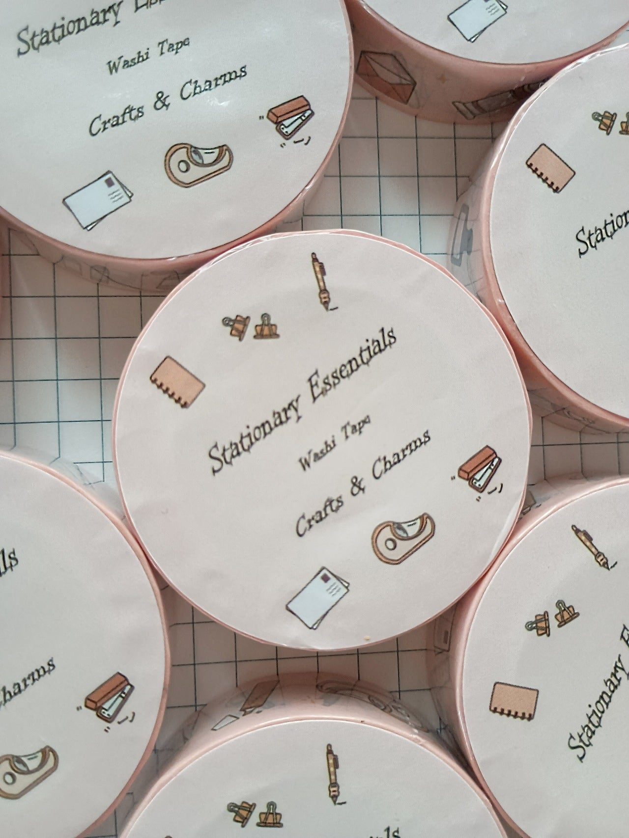 Washi tape labeled 'Stationary Essentials' with cute illustrations of every day stationary items on top  a book