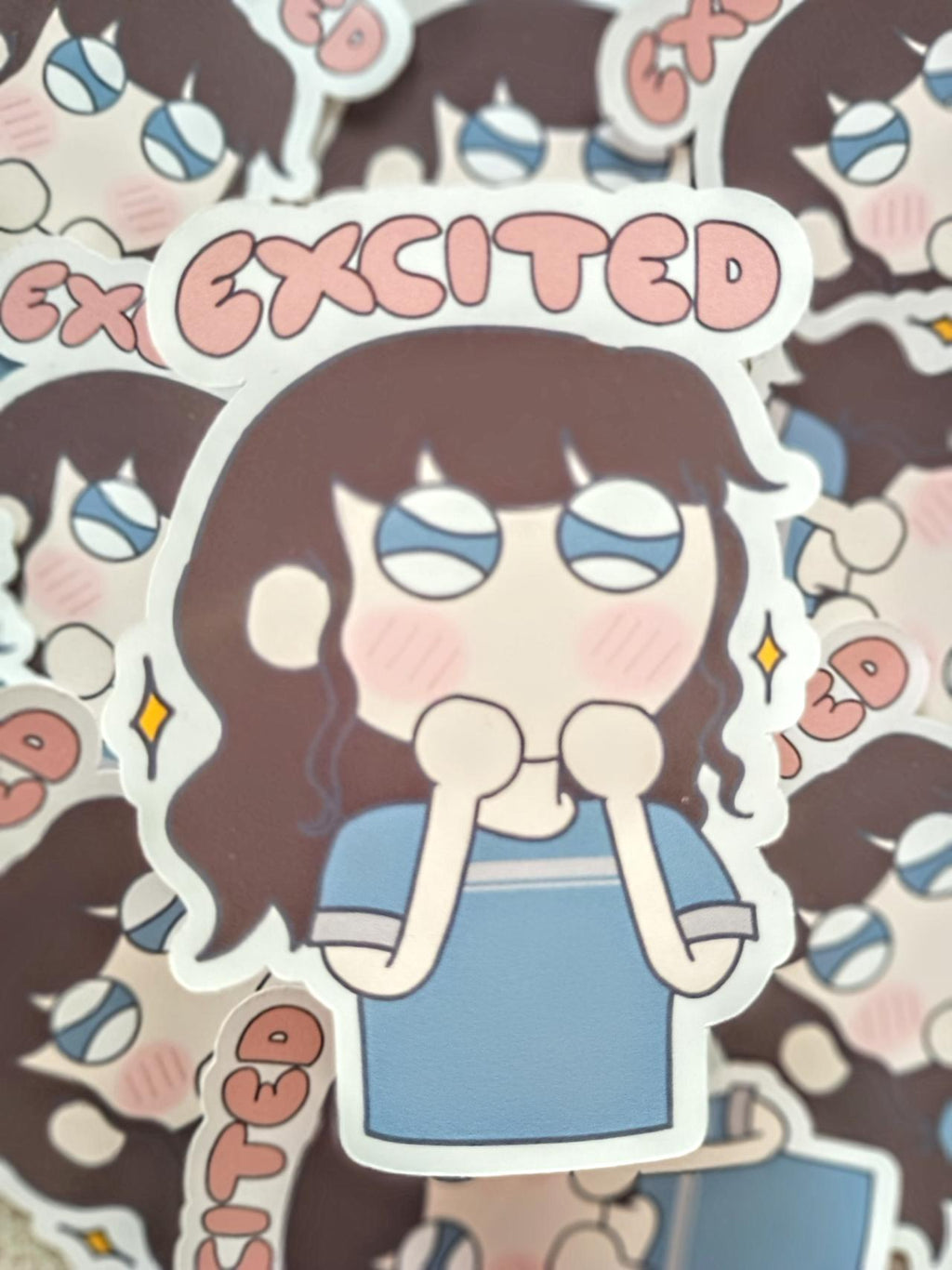 Sticker with girl in t-shirt in anime style art with an excited expression. the pink text on the sticker says exicited.