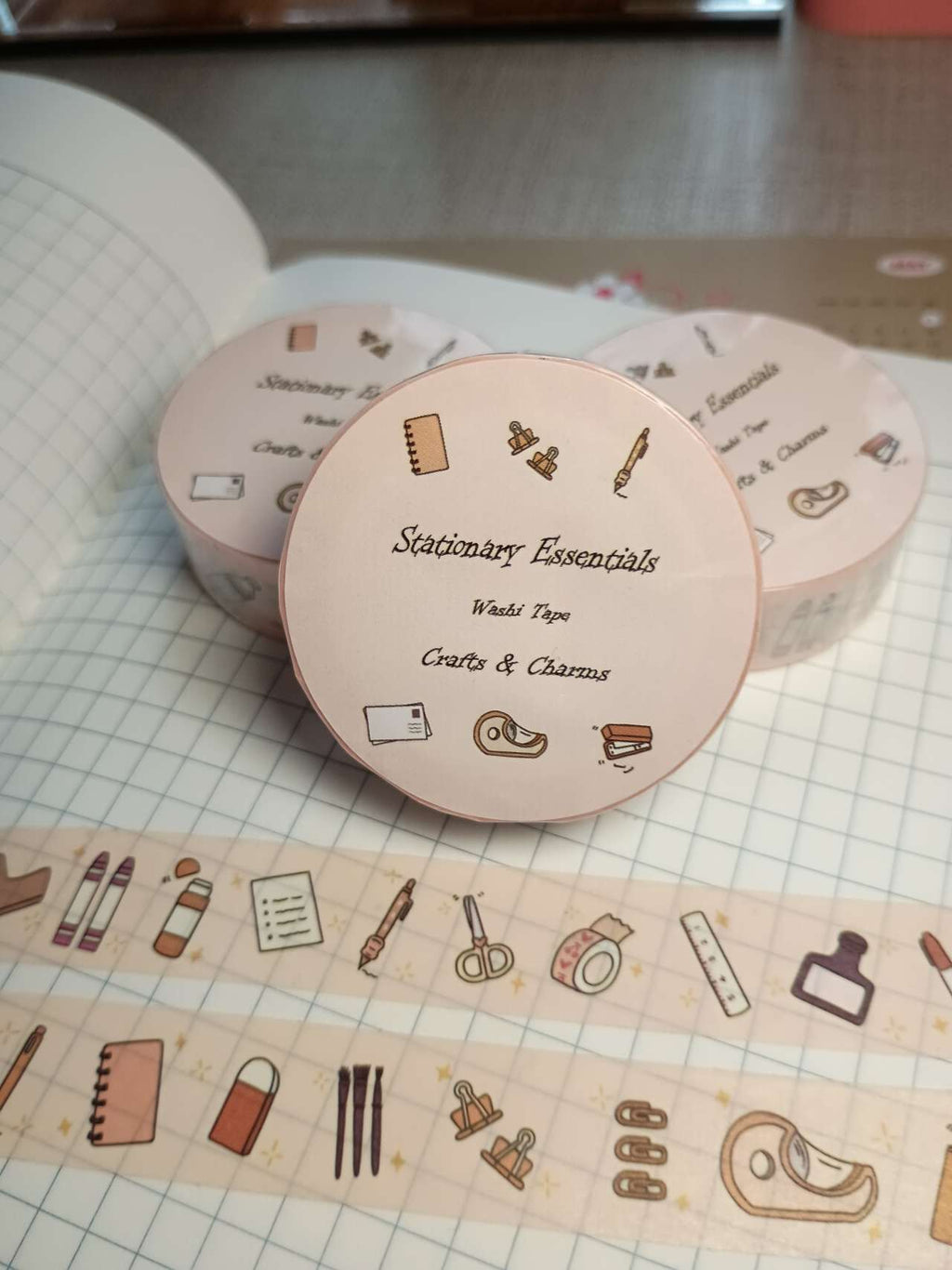 Washi tape labeled 'Stationary Essentials' with cute illustrations of every day stationary items on top  a book